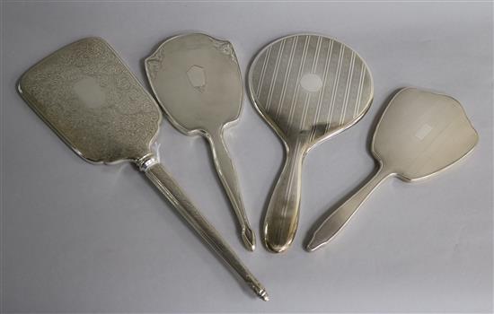 Four assorted 20th century silver hand mirrors including three engine turned and one with foliate engraving, largest 37.8cm.